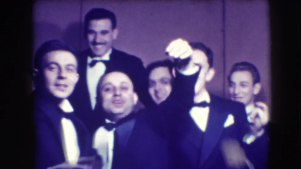 Men in tuxedos and bow ties face the camera in this 1941 Joliet home movie, smiling and raising hands in celebration.