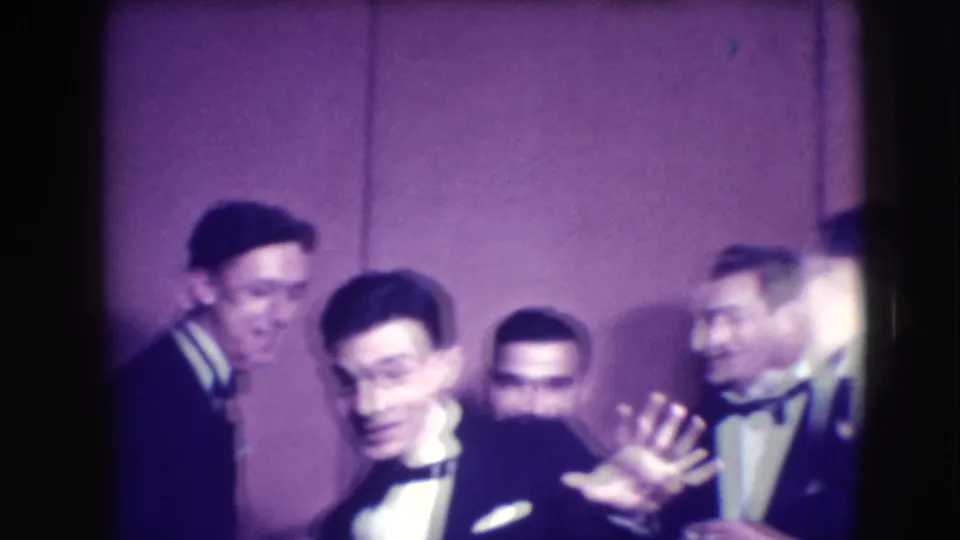 Several men in tuxedos lean and smile near the camera in Joliet, Illinois 1941, with one open hand raised in a playful gesture.