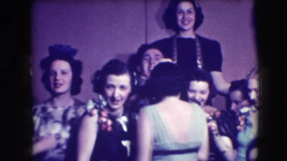 The home movie shows a larger formal group in 1941 Joliet, with faces turned toward the camera and one woman seen from behind.