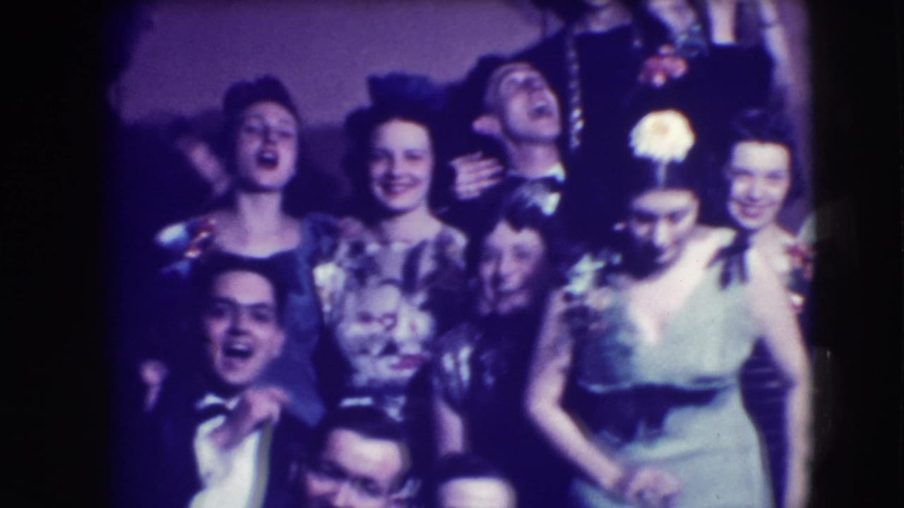 Adults in formal eveningwear smile and pose closely together indoors.