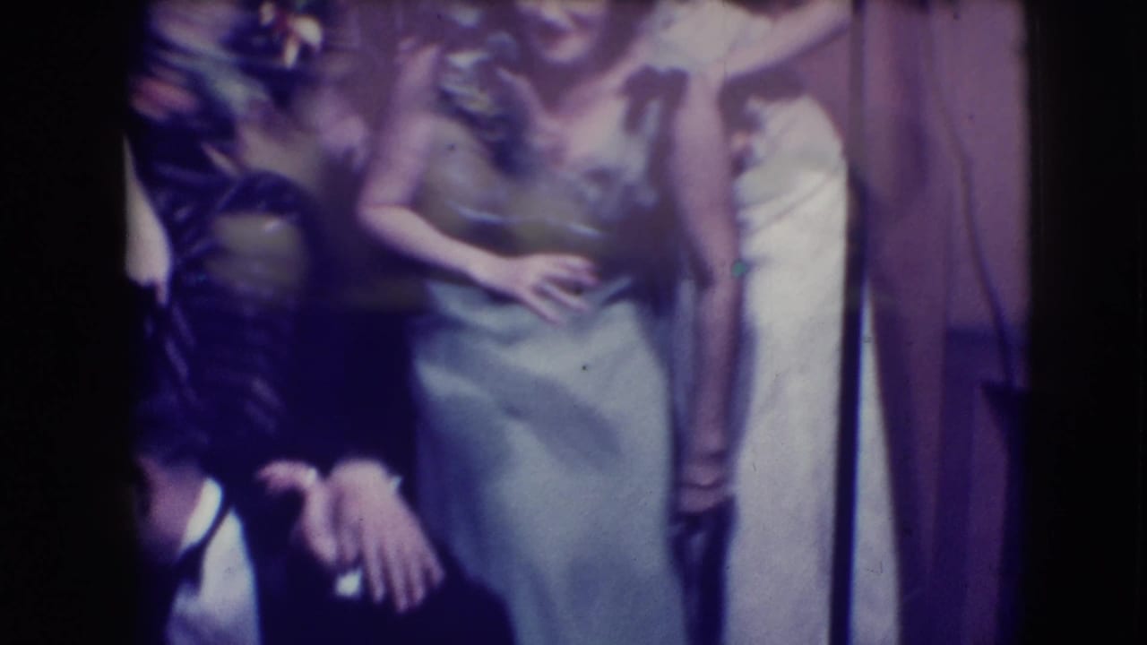 Cropped view of formally dressed young people standing close together near an interior wall.