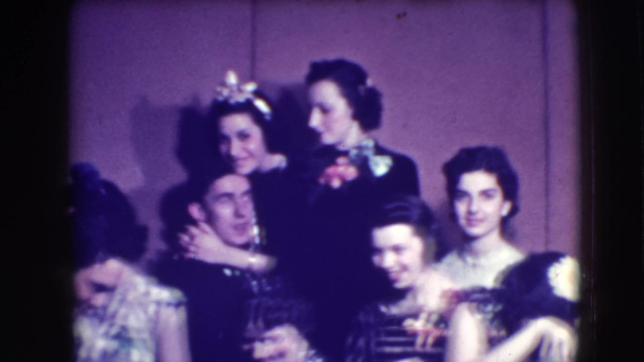 Adults in formal dress pose closely together in a dim interior.