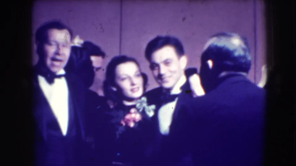 Formally dressed adults stand shoulder to shoulder in Joliet, Illinois, with one man turned away and others facing the camera.