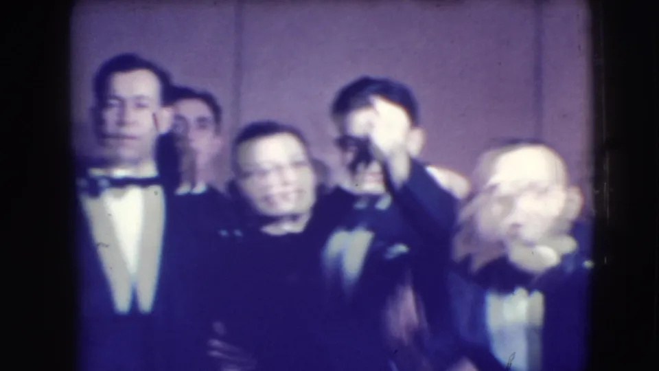 Several formally dressed adults appear close to the camera in the 1941 Joliet home movie, with one man partly blurred by motion.