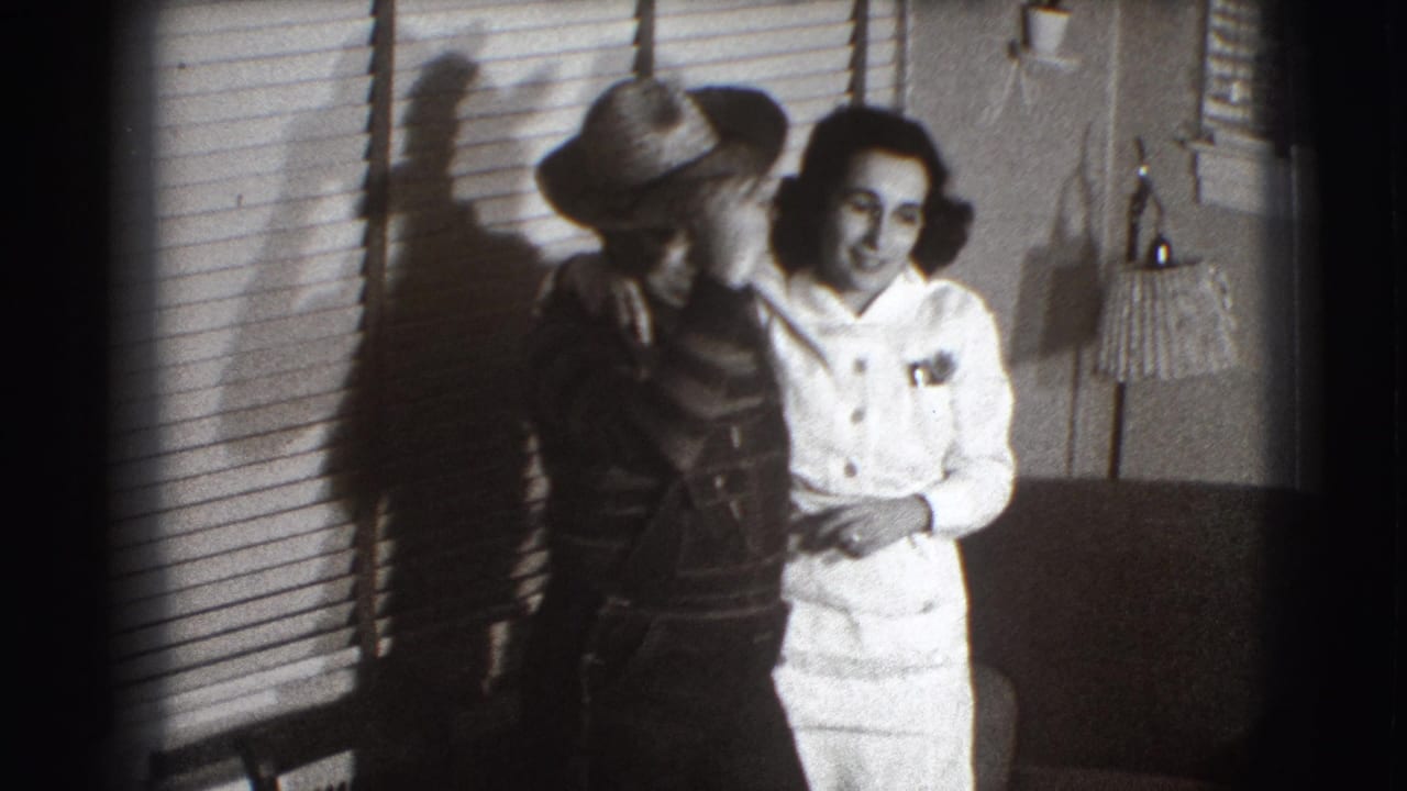 Adult couple standing close beside window blinds in a private room.