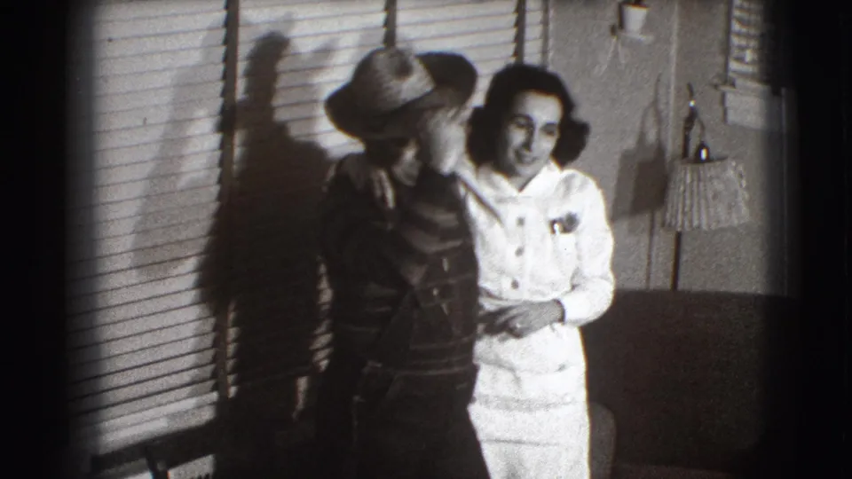 In Joliet, Illinois, 1941 home-movie footage, an adult couple poses together indoors beside venetian blinds and a lamp.