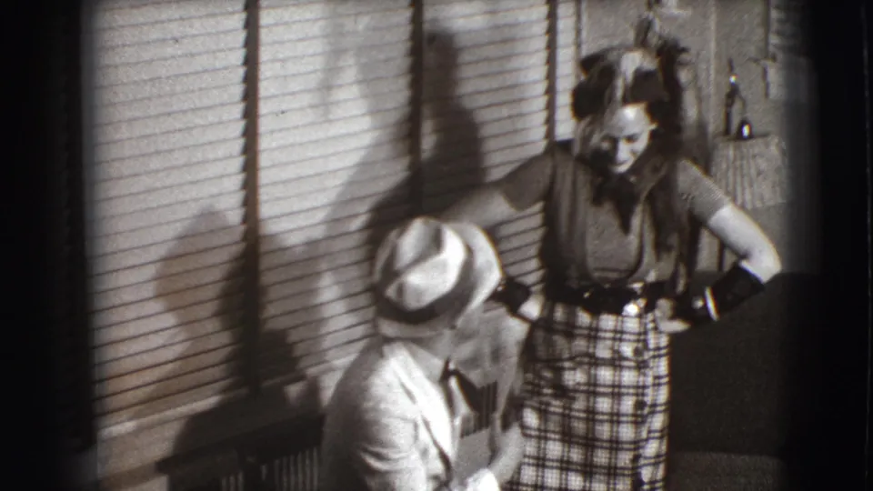 In this Joliet 1941 home-movie frame, the seated man looks up toward the standing woman as she leans slightly with hands at her waist.