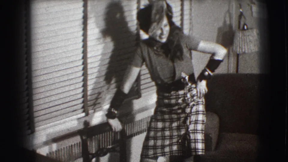 A black-and-white frame shows the woman posing in a 1941 Joliet living room, with blinds, radiator, chair, and lamp in view.