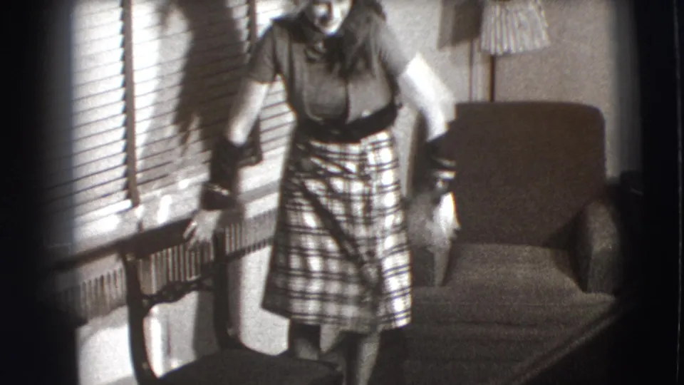 The final frame crops the woman as she shifts near the chair and blinds in the supported 1941 Joliet home interior.