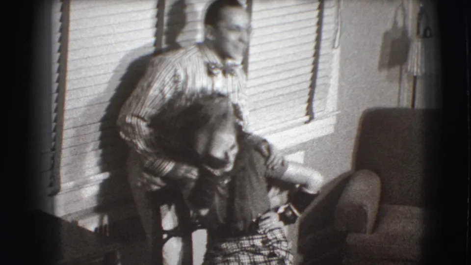 In the final 1941 Joliet frame, the seated woman bends forward laughing while the man stands close behind her beside window blinds and an armchair.