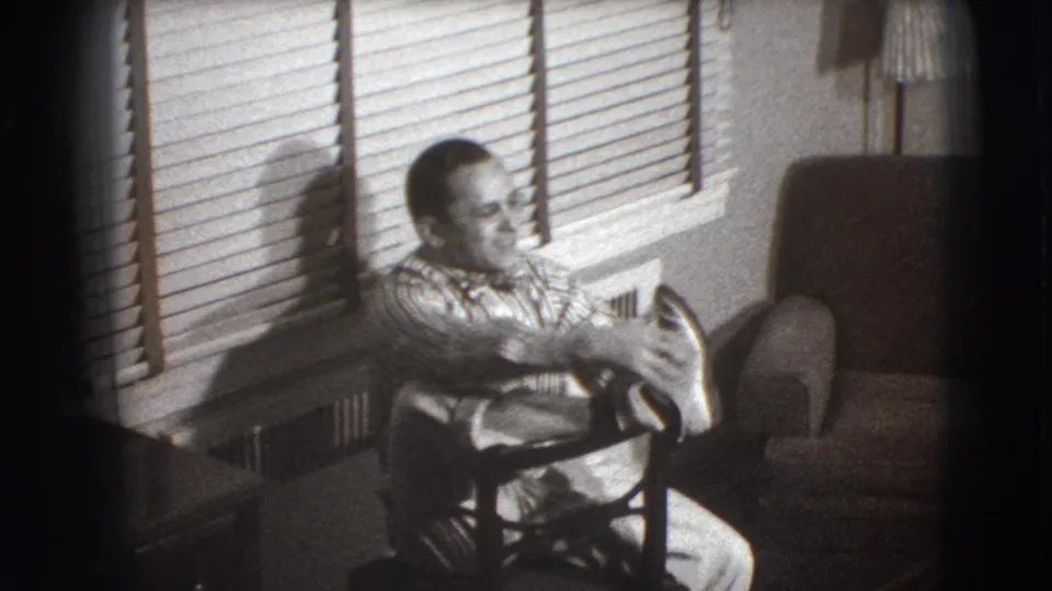 In Joliet, Illinois, a man with glasses sits near venetian blinds during a 1941 home-movie medical-care scene.