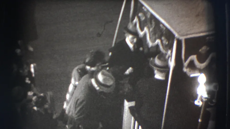 The final frame shows mourners gathered tightly beside the draped casket in the Joliet, Illinois funeral footage.