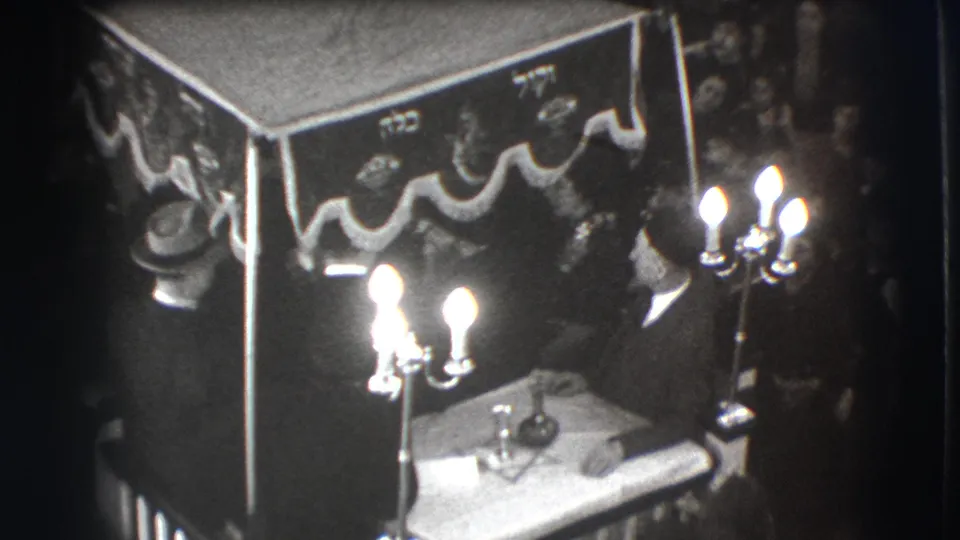 High-angle 1941 Joliet frame with a draped canopy, bright candelabras, small table, and people gathered closely around the scene.