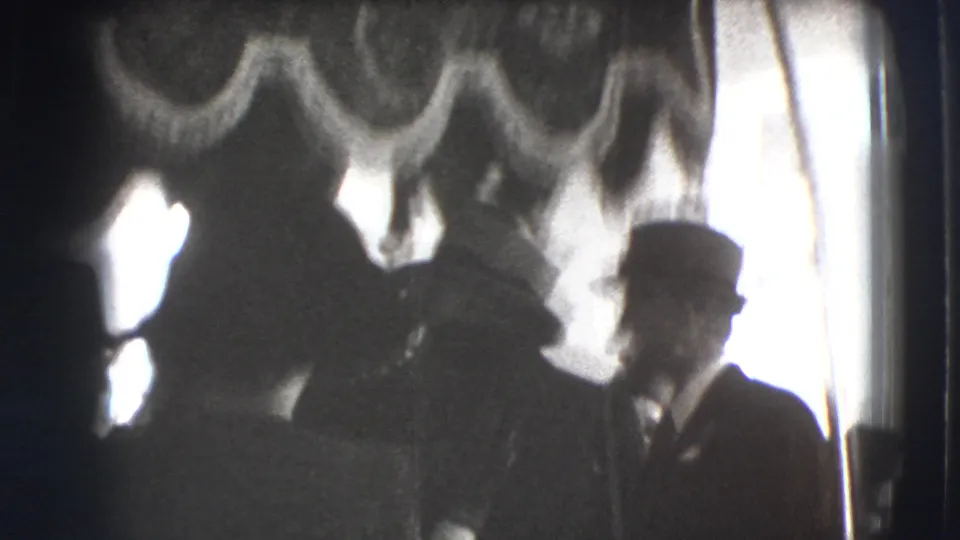 1941 Joliet frame with men and women in hats gathered under a tasselled canopy, mostly in silhouette.