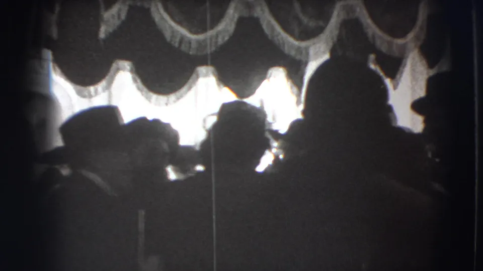 Joliet 1941 home-movie frame showing an audience-like group from behind, with strong backlight and canopy tassels overhead.