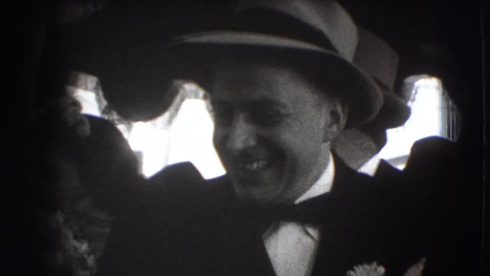 Close home-movie view of a smiling man in formal dress at a 1941 Joliet indoor celebration or gathering.