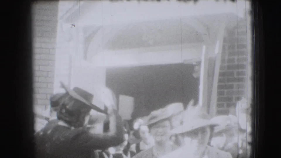 A brief exterior view shows men in hats near a building entrance, likely adjacent to the same 1941 Joliet gathering.