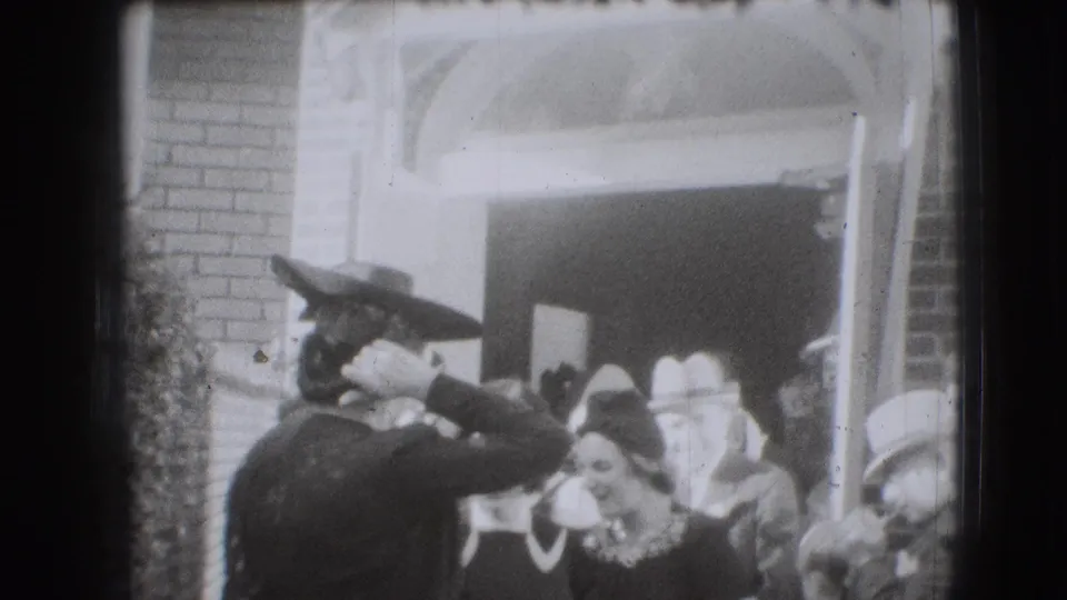 Women in 1940s-style hats and dresses smile and talk outside an arched brick entrance in Joliet, Illinois, according to metadata.