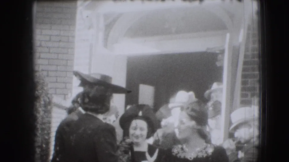 A soft 8mm frame shows women in hats and dresses moving through a crowded brick doorway during a 1941 Joliet event exit.