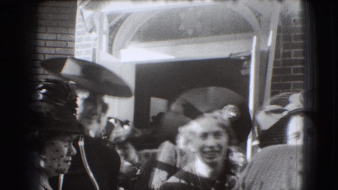 Crowd in hats and dresses gathered outside a brick building entrance.