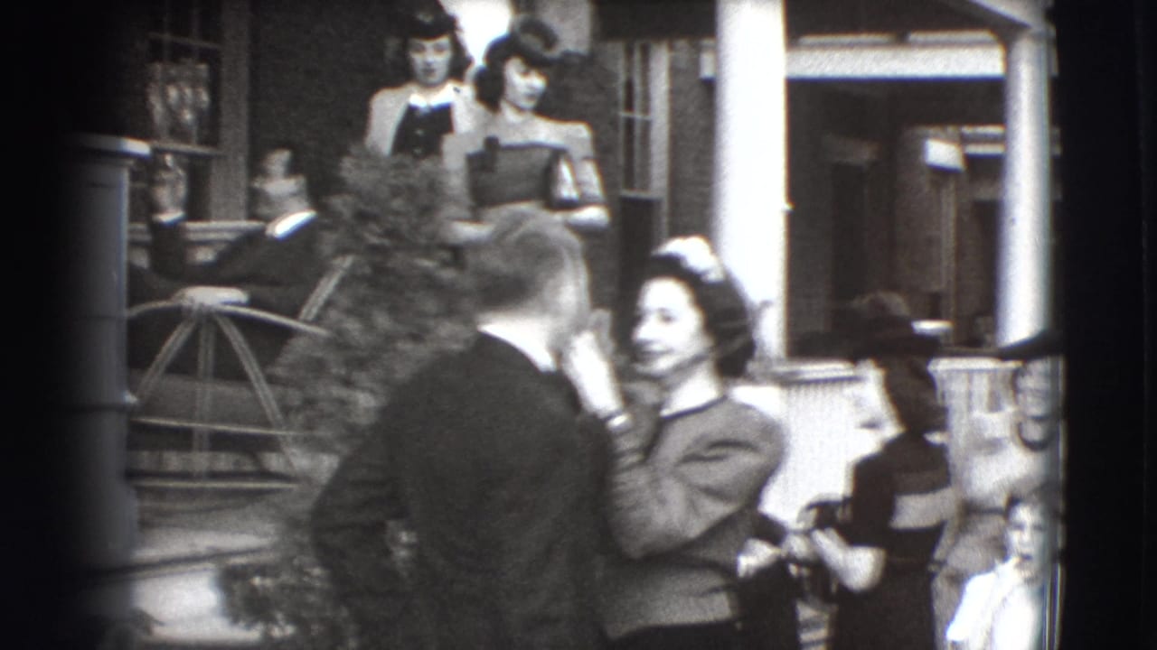 Woman touches a man's face on a porch while several adults stand or sit nearby.