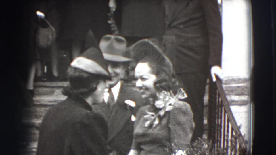 A group of formally dressed guests in Joliet, Illinois, 1941, converse on porch steps, including men in hats and a woman with corsage.