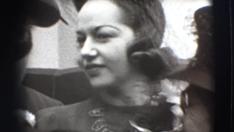 A woman smiles in close-up in the Joliet, Illinois 1941 home movie, framed by adults wearing formal hats.