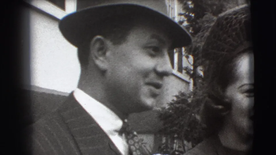 The formally dressed man appears in profile near a woman with dark hat or veil detail in Joliet, Illinois footage from 1941.