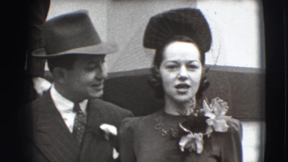 1941 Joliet home-movie frame showing a formally dressed couple facing the camera, with the man smiling toward the woman.