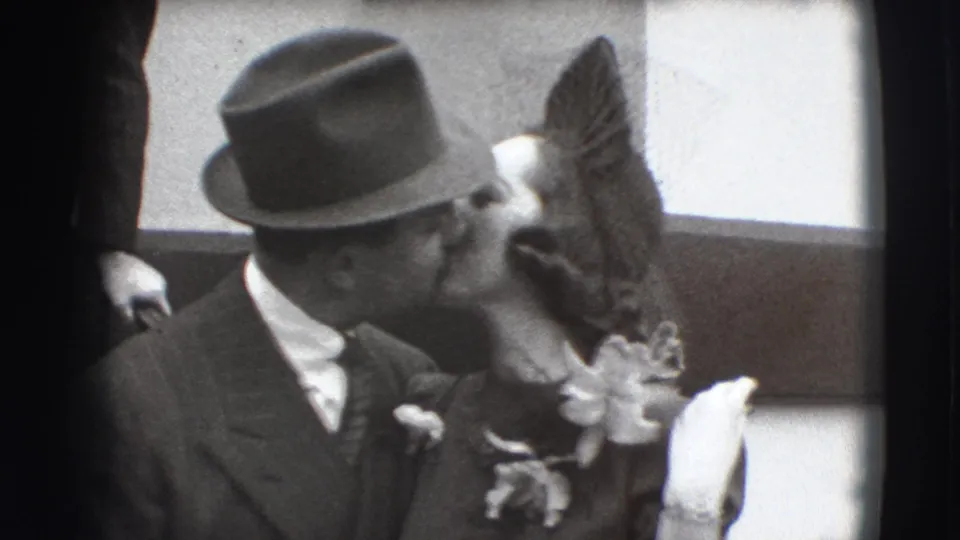 1941 Joliet home-movie moment of a formally dressed man leaning in to kiss the woman beside him.