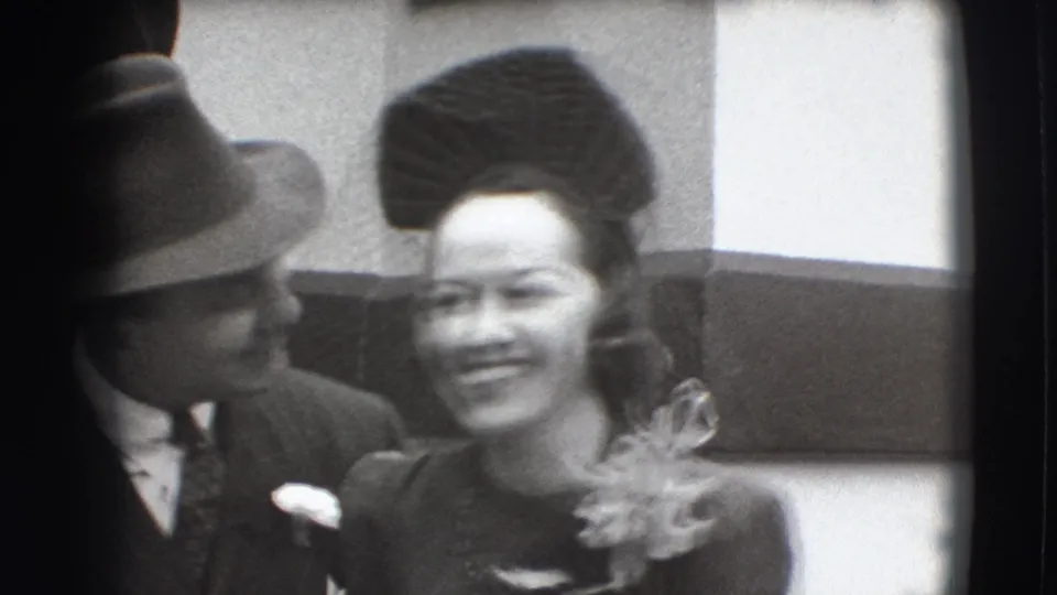 In 1941 Joliet home-movie footage, a formally dressed man in a fedora stands close to a smiling woman wearing a sculpted hat.