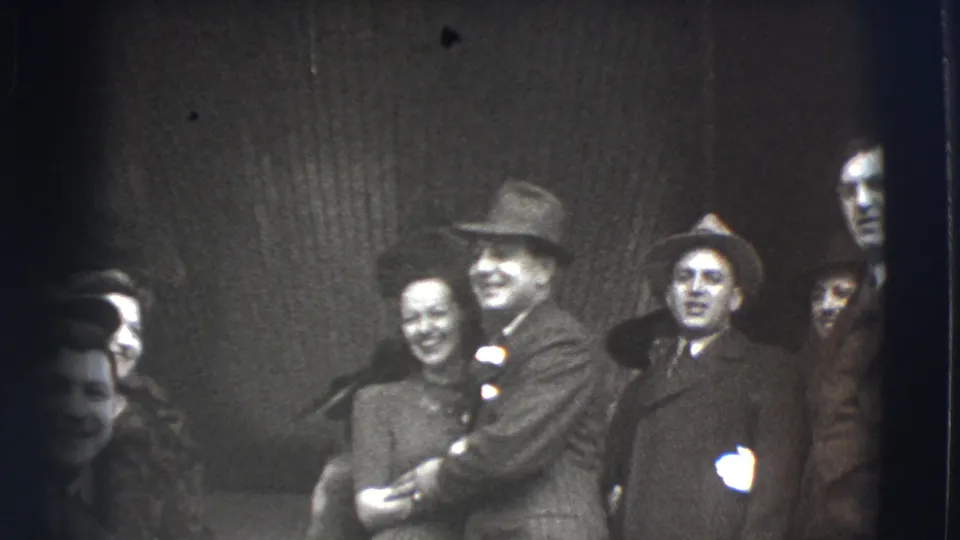 The 1941 Joliet footage shows a suited man in a fedora embracing a smiling woman as other adult guests stand around them.