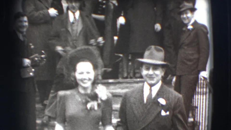 In 1941 Joliet, Illinois, a smiling wedding couple appears outside a church with guests gathered on the steps behind them.