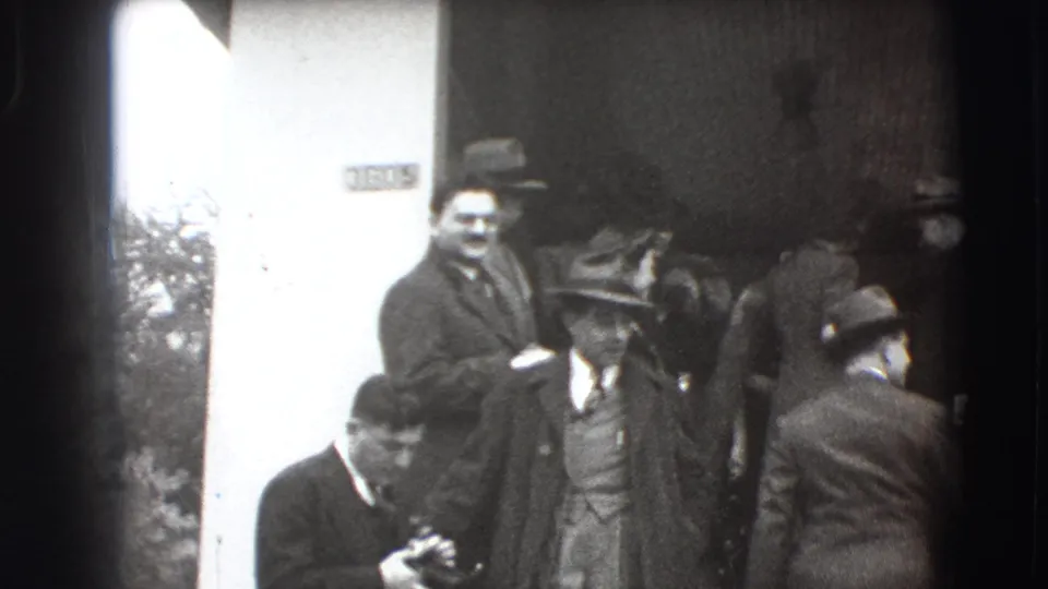 Guests in formal coats and hats gather near the church entrance in this 1941 Joliet wedding home-movie frame.