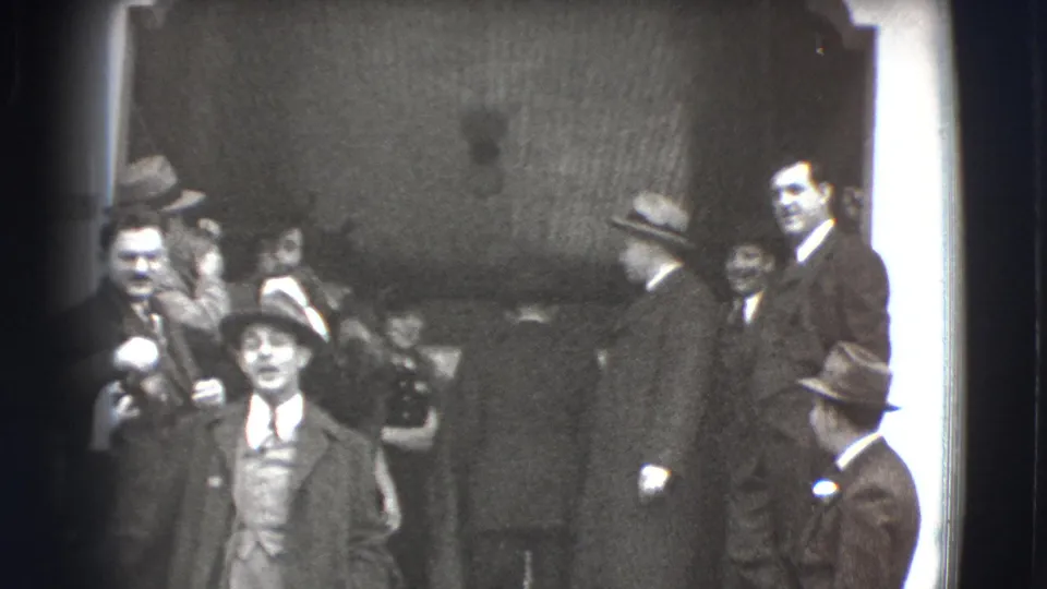 In Joliet, Illinois, 1941, formally dressed adults gather on chapel-like steps as men in brimmed hats and a woman in a fur coat face the camera.