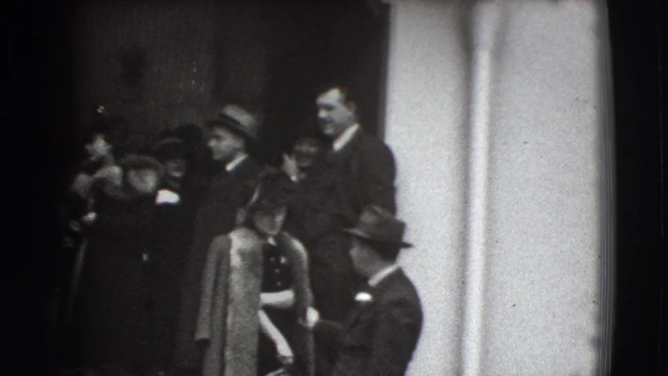 Formally dressed adults cluster near a chapel-like entrance in 1941 Joliet footage, with a fur-coated woman prominent on the steps.