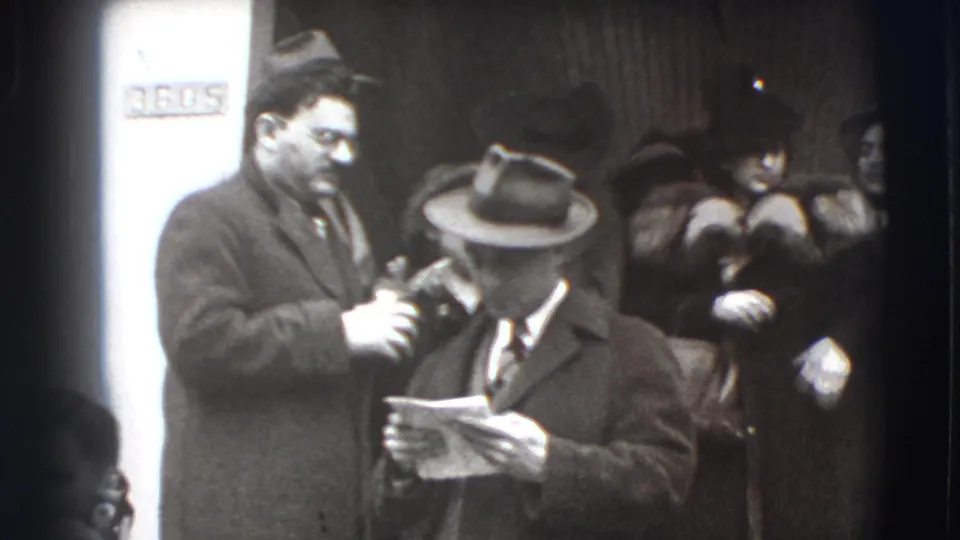 In the final 1941 Joliet frame, a man in a fedora holds a paper while another suited man stands beside him and guests remain in the entrance.