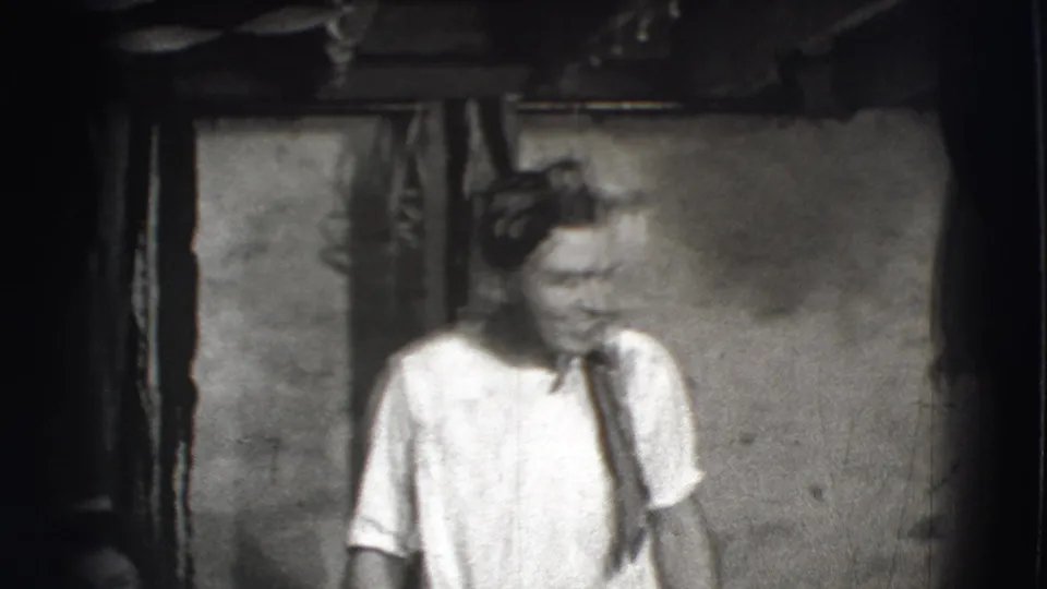 In 1941 Joliet home-movie footage, a man in a white shirt and tie appears to perform in a dim rustic interior.
