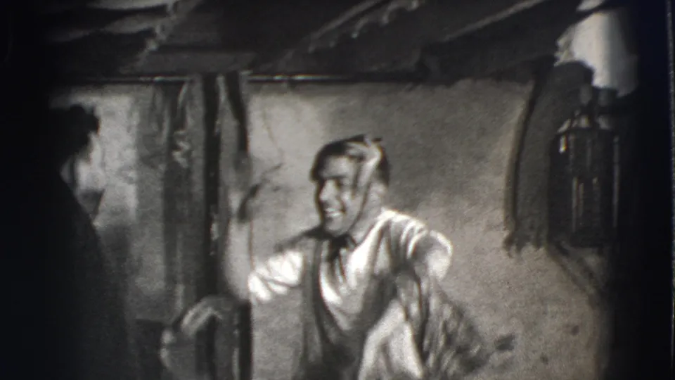 Joliet, Illinois 1941 frame showing a smiling adult man in a light shirt bending forward during playful movement in a basement.