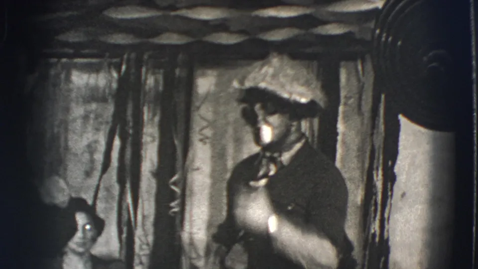 The Joliet performer stands before draped curtains, wearing a brimmed hat and holding a white pipe close to his mouth.
