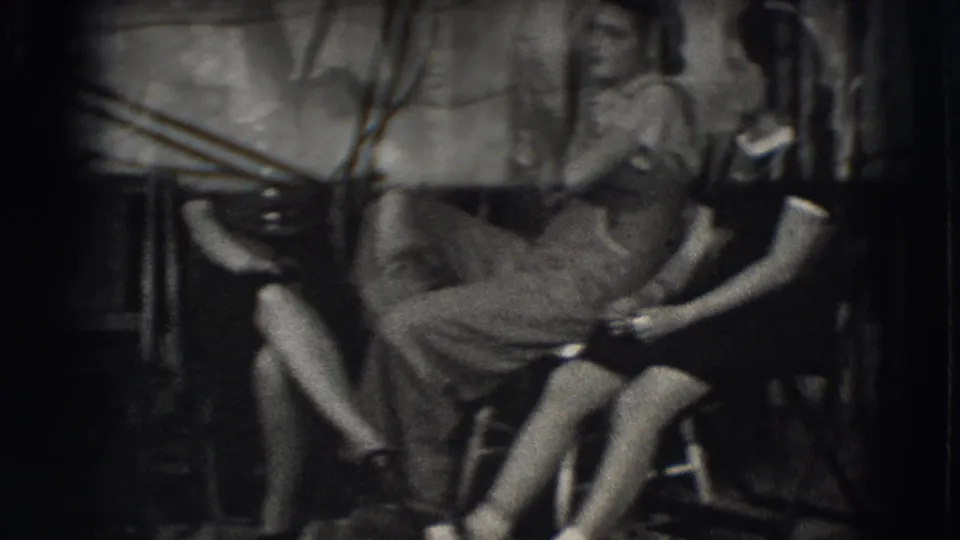In 1941 Joliet, Illinois home-movie footage, young women sit close together outdoors against a rough wall.
