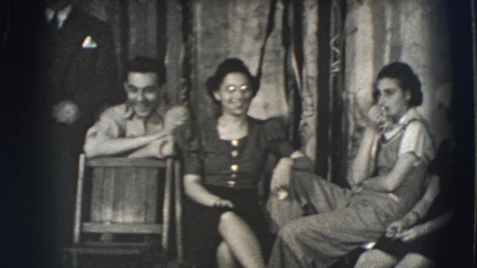 Young adults in 1941 Joliet, Illinois relax outdoors, with a suited man partly visible behind seated friends.