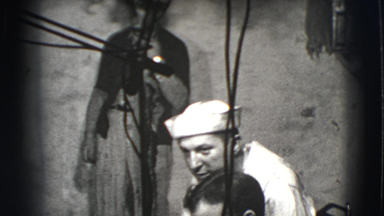 Man in a white sailor cap leaning beside another man in a dim interior.