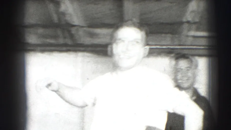 Overexposed 1941 Joliet home-movie frame showing a man facing the camera with another smiling man partly visible behind him.