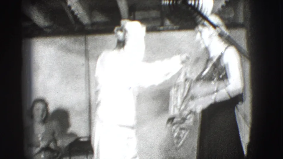 The man in white gestures toward the woman in a dark dress as seated spectators watch the 1941 Joliet stage routine.