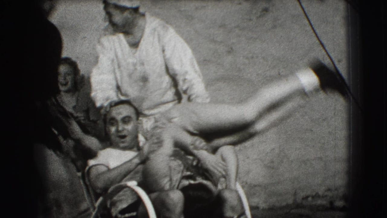 Sailor lifts a woman while adults watch and smile in a crowded black-and-white home-movie frame.