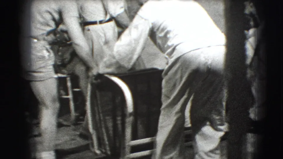 The 1941 Joliet footage shows the white-clad man bending over the metal frame as nearby adults steady or observe the object.