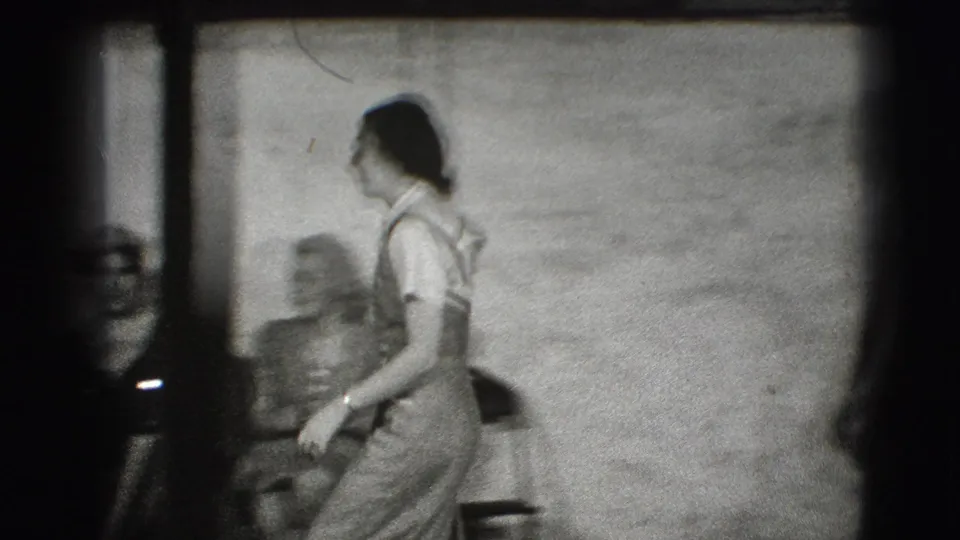 A woman moves across the room past a seated older woman, continuing the informal 1941 Joliet home-movie interior scene.