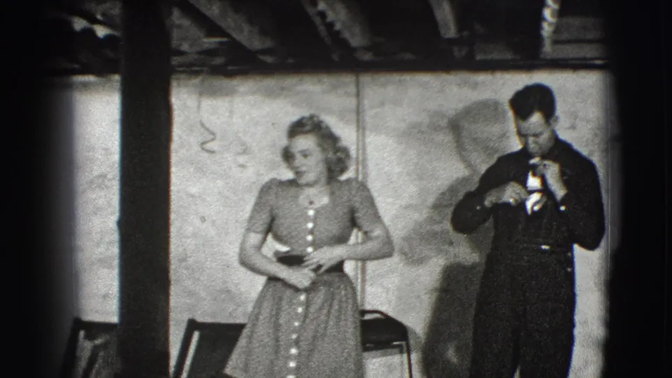 The man looks down and handles the small gift or award while the woman stands nearby in the 1941 Joliet home-movie scene.