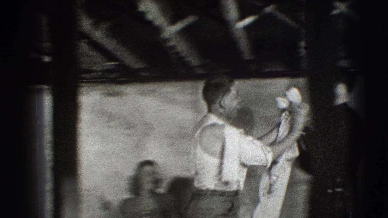 Man in a white shirt holds a light cloth in a dim interior.
